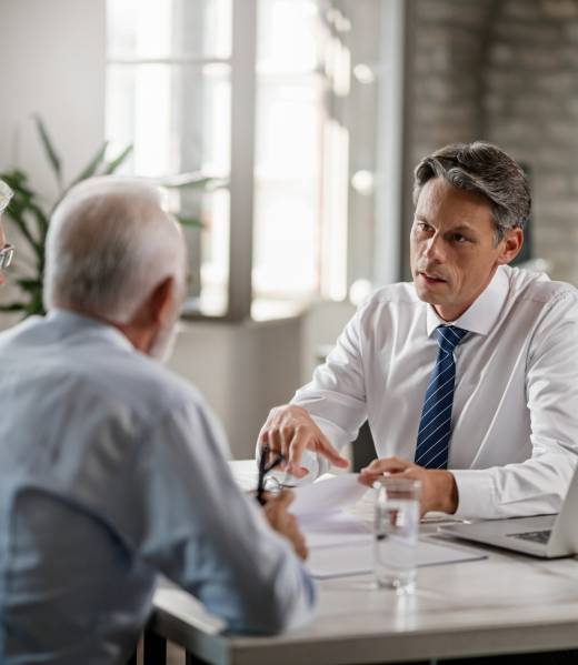 Mid adult insurance agent with mature couple analyzing financial reports and communicating during the meeting in the office.